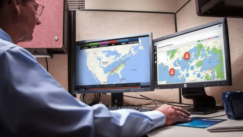 Dispatcher monitoring fleet tracking maps on dual screens